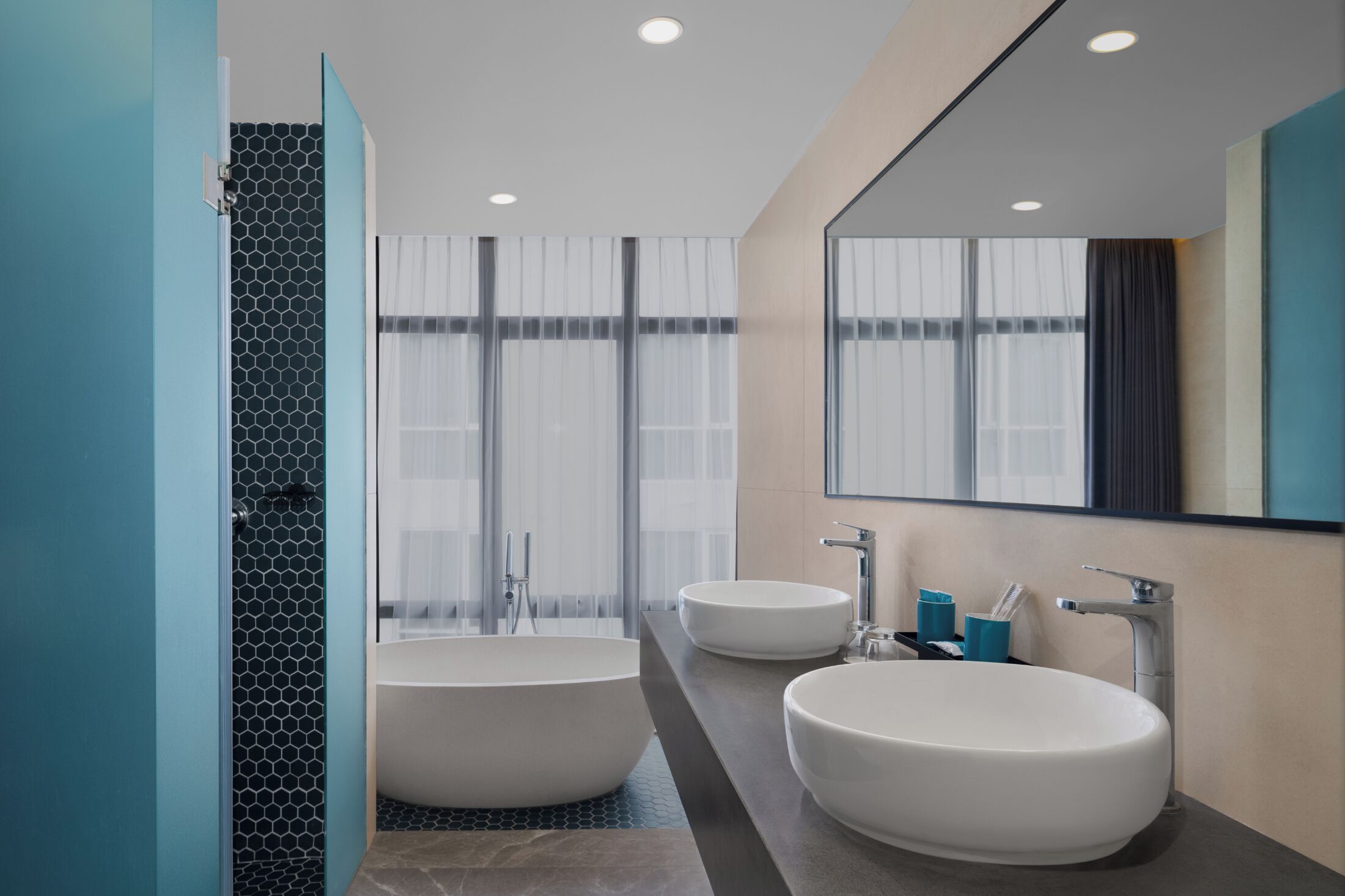 Une salle de bain moderne avec deux lavabos, une baignoire et un grand miroir.