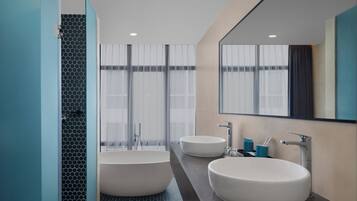 Une salle de bain moderne avec deux lavabos, une baignoire et un grand miroir.
