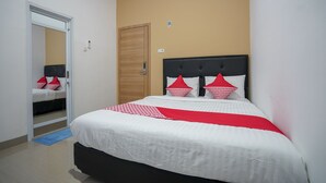 A bedroom with a bed, a wooden door, and a mirror. - OYO 945 Mega Kost 2 (Palembang)