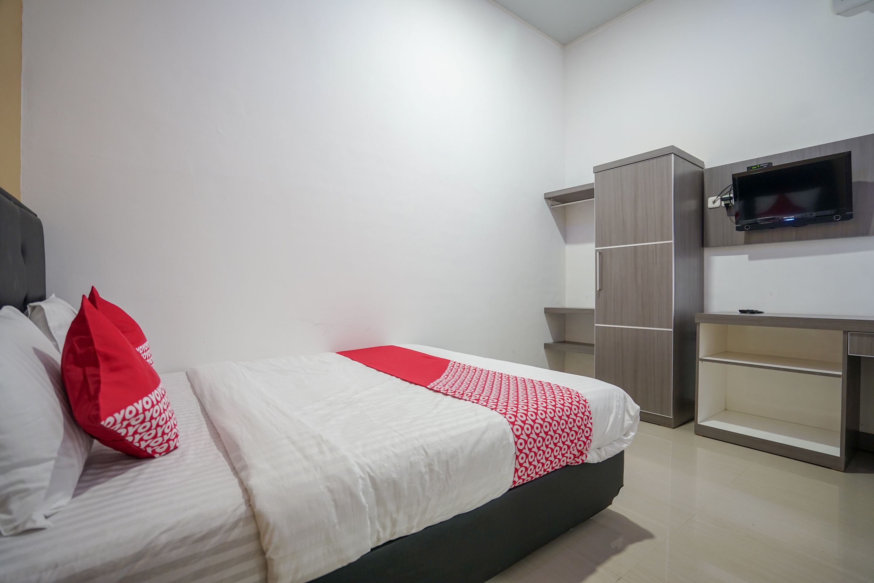 A modern bedroom with a bed, a TV mounted on the wall, and built-in storage units.