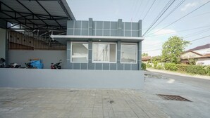 A modern building with a flat roof, large windows, and a paved entrance area. - OYO 945 Mega Kost 2 (Palembang)