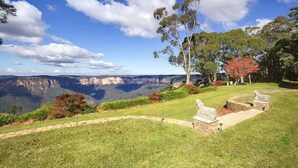 A scenic view of a park with a pathway, benches, and a view of a canyon.