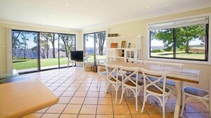 A spacious room with a large sliding glass door leading to a garden, a wooden table with chairs, and a built-in shelf unit.