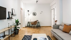 A modern living room with a sofa, coffee table, and a dining area with a chair and table. - Bright 2BD Apartment in Psychiko (Neo Psichiko)