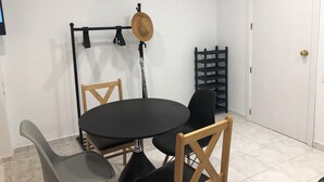 Pieni ruokailutila, jossa on pyöreä pöytä, kaksi puutuolia, musta tuoli, seinäkello ja ovi.