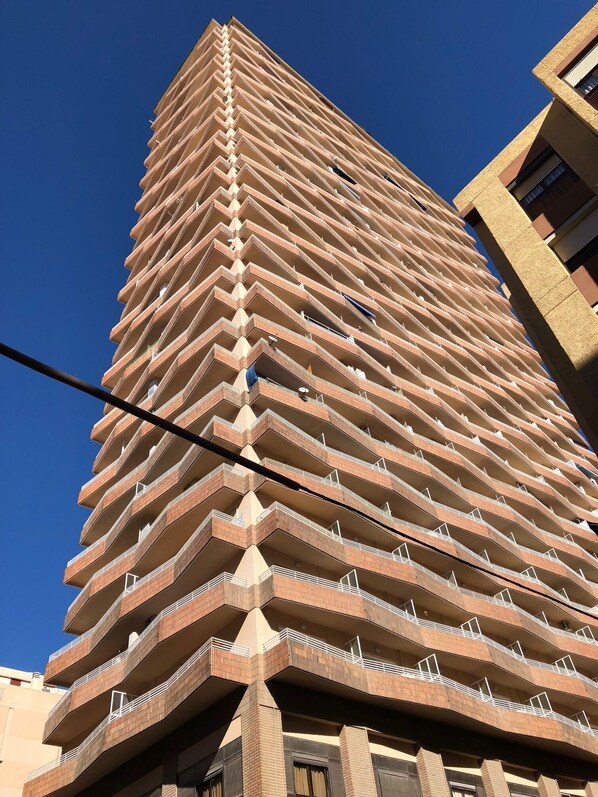 A tall, multi-story building with a unique zigzagged architectural design, featuring balconies on each floor.
