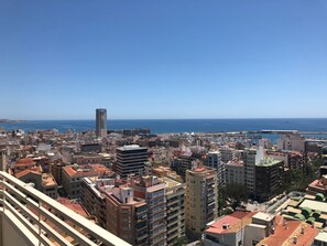 A coastal cityscape with a variety of building styles, including a prominent tower and several multi-story residential and commercial buildings.