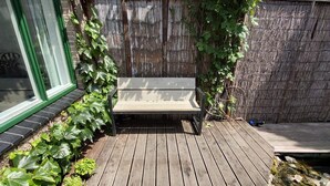 Eine Holzterrasse mit einer Bank, umgeben von einem Holzzaun und viel Grün.