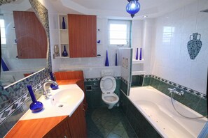 Une salle de bain avec un lavabo blanc, des toilettes et une baignoire.