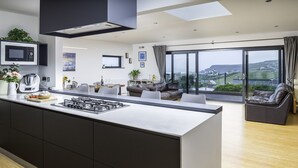 Una cocina moderna con una isla central, un área de comedor con sofá y un amplio ventanal con vistas al campo.