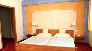 Ein Doppelbett mit Holz-Kopfstück, zwei Nachttische mit Lampen und ein roter Teppichboden.