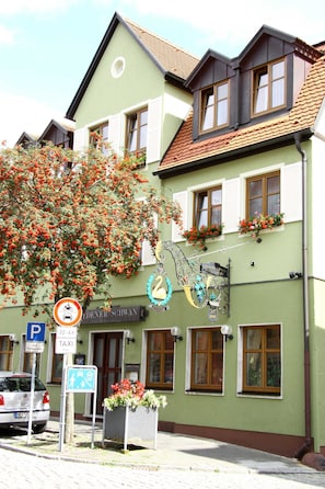 Ein Gebäude mit grüner Fassade, zahlreichen Fenstern und Blumenkästen.