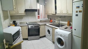 Cocina compacta con estufa, microondas, lavamanos y lavadora.
