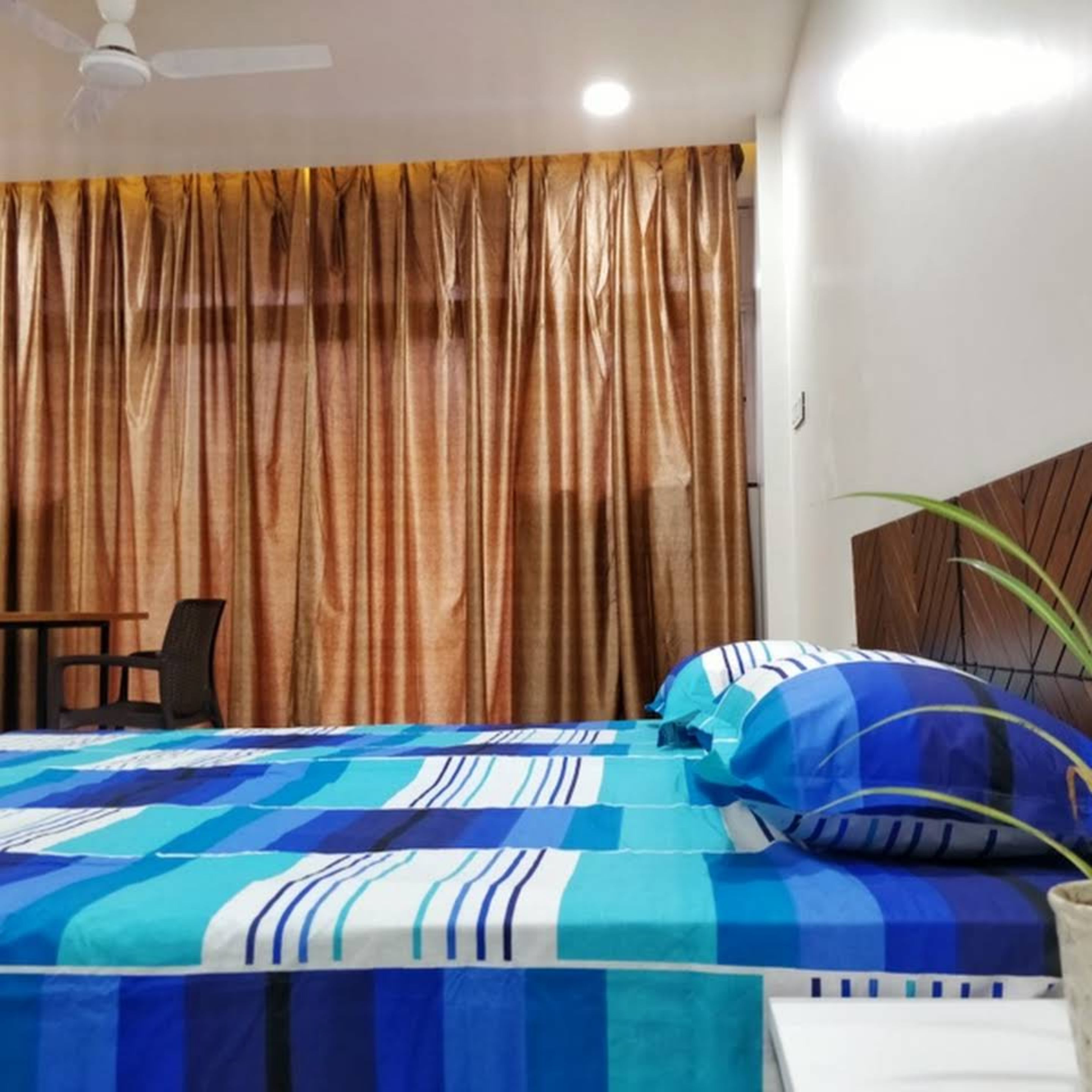 A bedroom with a bed, a chair, and a ceiling fan.