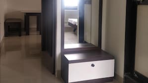 A hallway with a mirror, a small table, and a bed visible through the mirror. - RP Studio Rooms (Igatpuri)