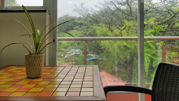 A room with a tiled floor, a potted plant, and a view of trees through a window. - RP Studio Rooms (Igatpuri)