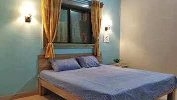 Un dormitorio con cama, cortinas, una mesita de noche y una ventana.