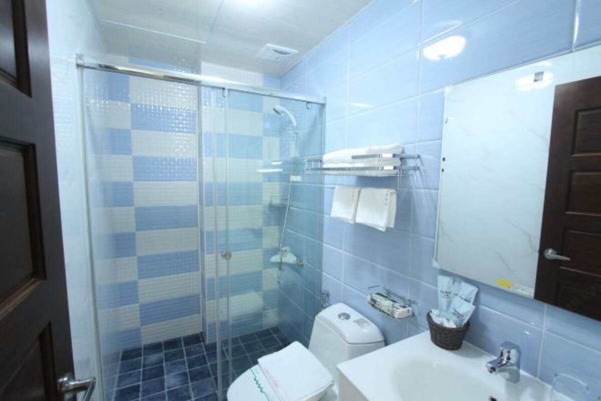 A bathroom with a glass shower enclosure, a white sink, a toilet, and a mirror.