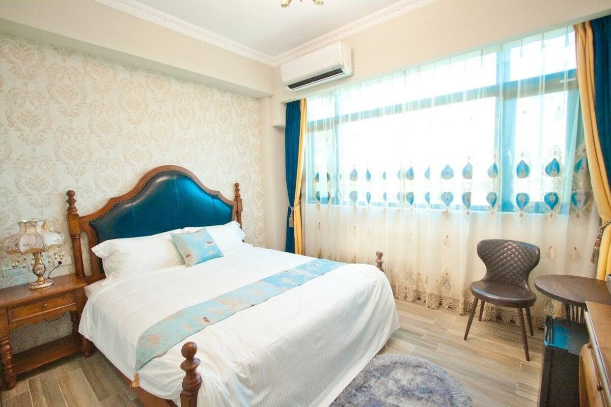 A bedroom with a large bed, a nightstand, a chair, and a small table.
