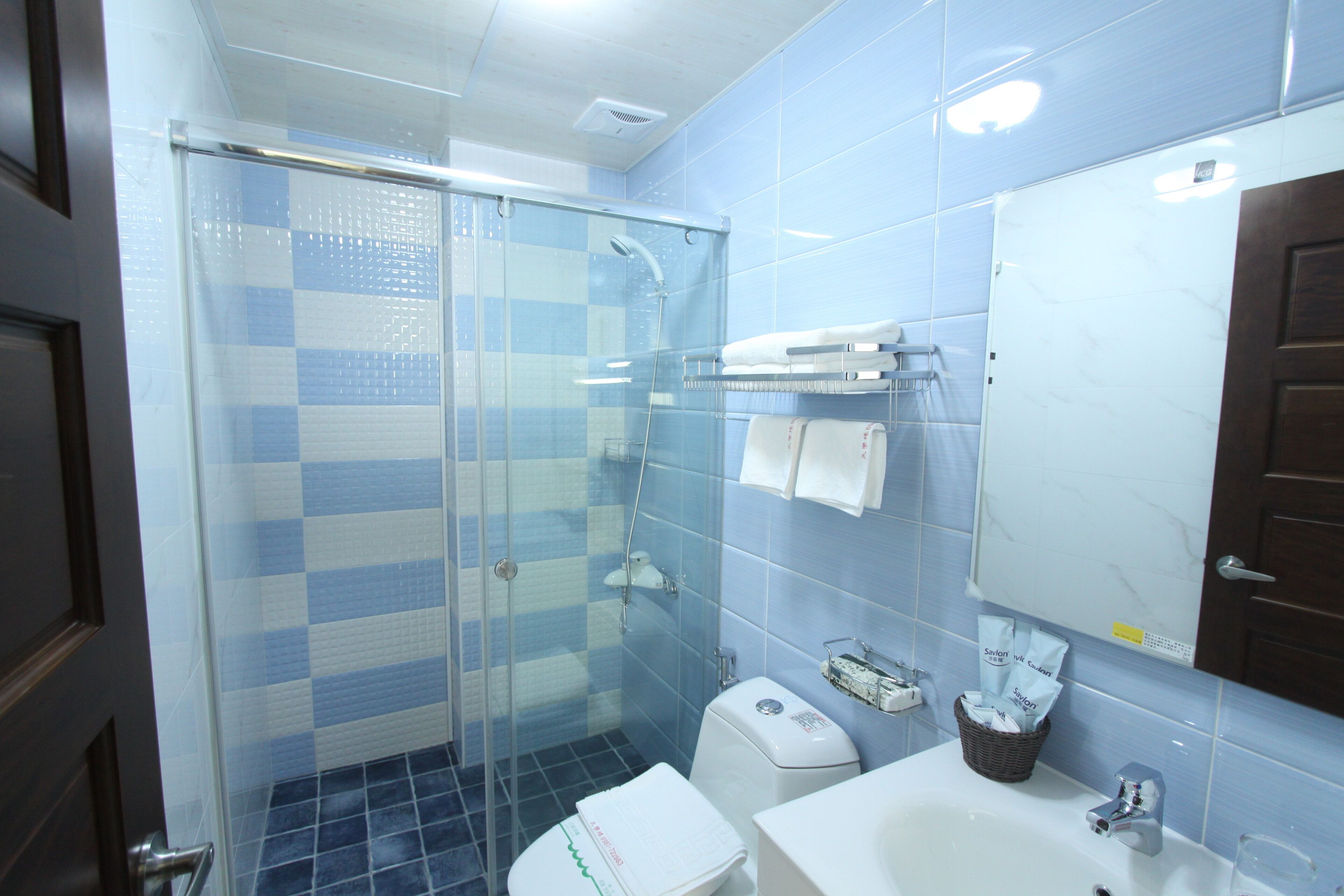 A bathroom with a glass shower enclosure, a white sink, and a mirror above the sink.