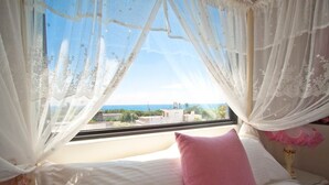 A bedroom with a bed, a pink pillow, and a view of buildings through sheer curtains. - Minleyuan (Hualien City)