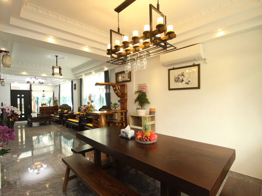 A spacious lobby with a wooden reception desk, a chandelier, and a dining area with a long table and benches.