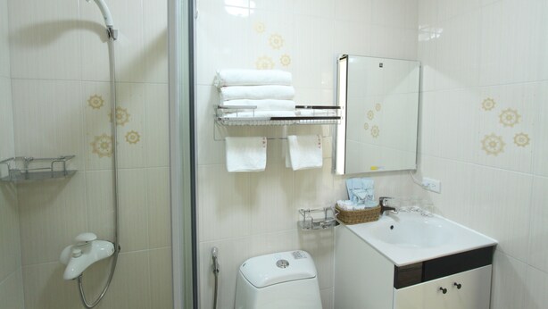A bathroom with a shower, toilet, sink, and towel rack. - Minleyuan (Hualien City)
