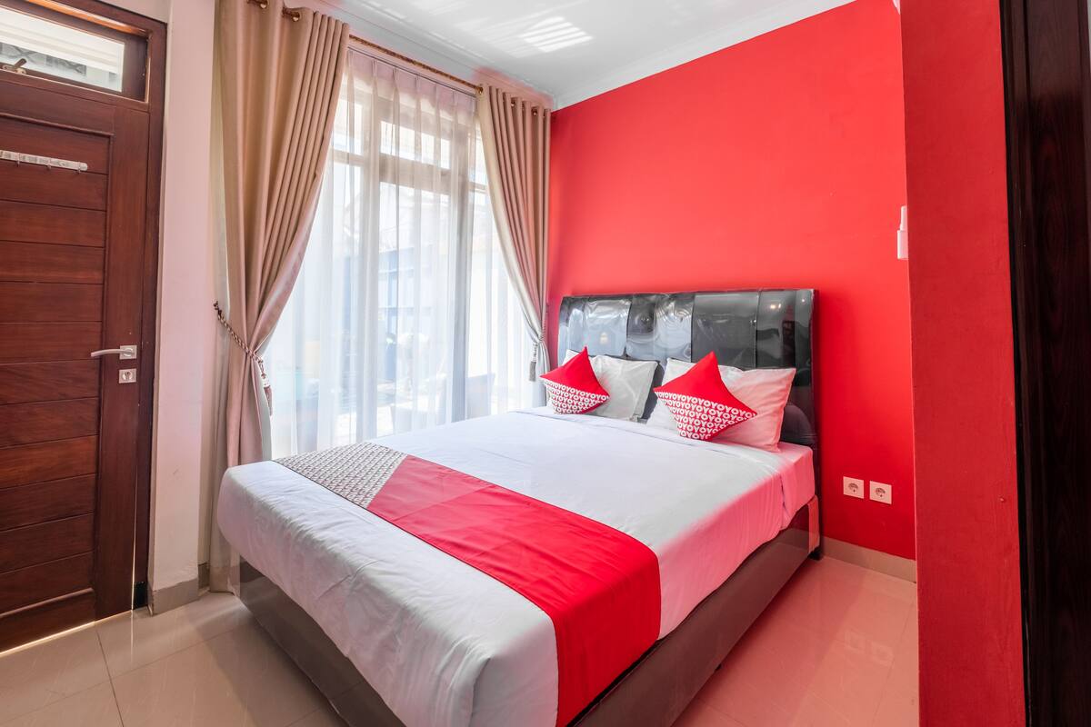 Una habitación de hotel con una cama grande, paredes rojas y una puerta de madera.