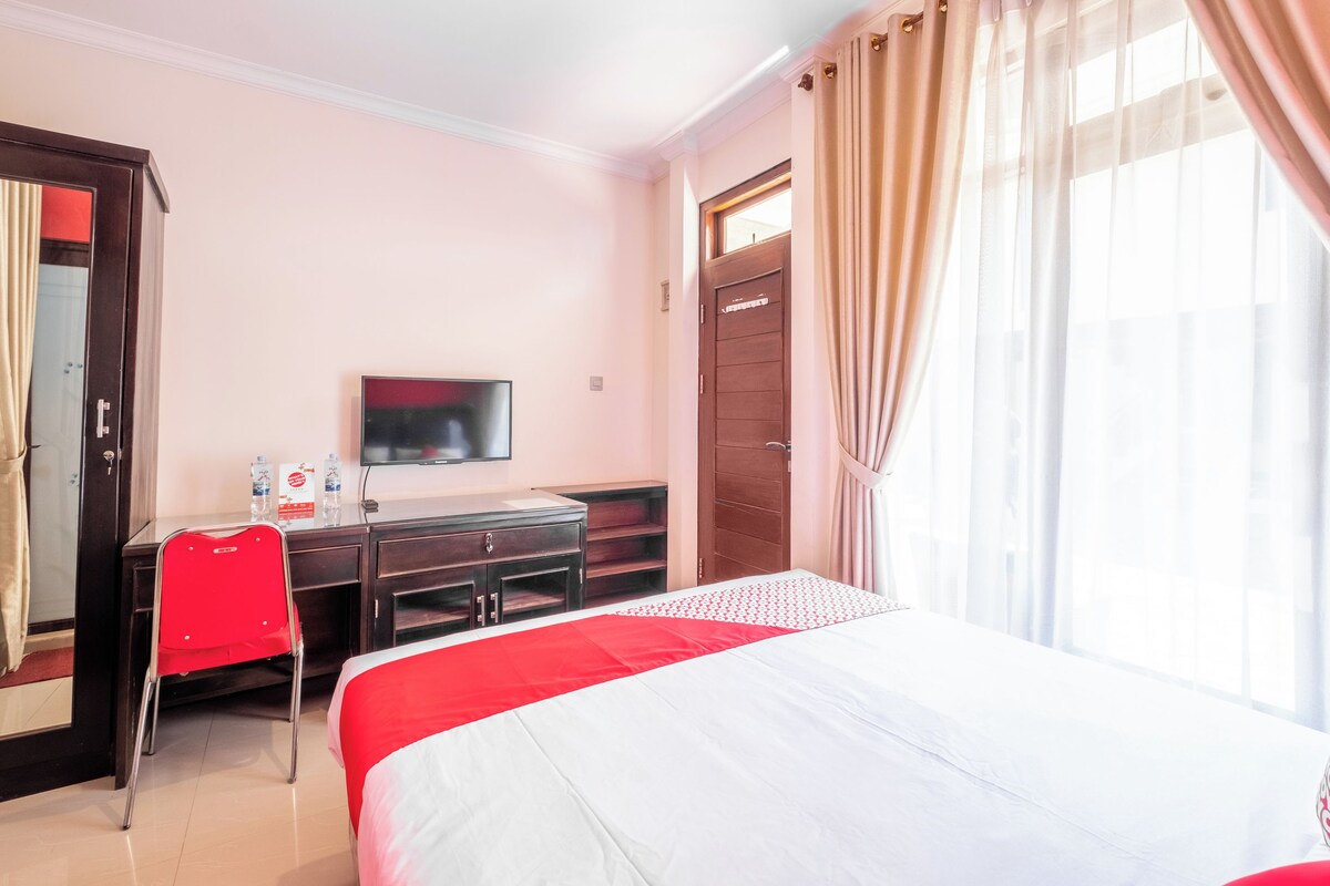 Habitació d'hotel amb llit, escriptori amb cadira, televisió i armari.