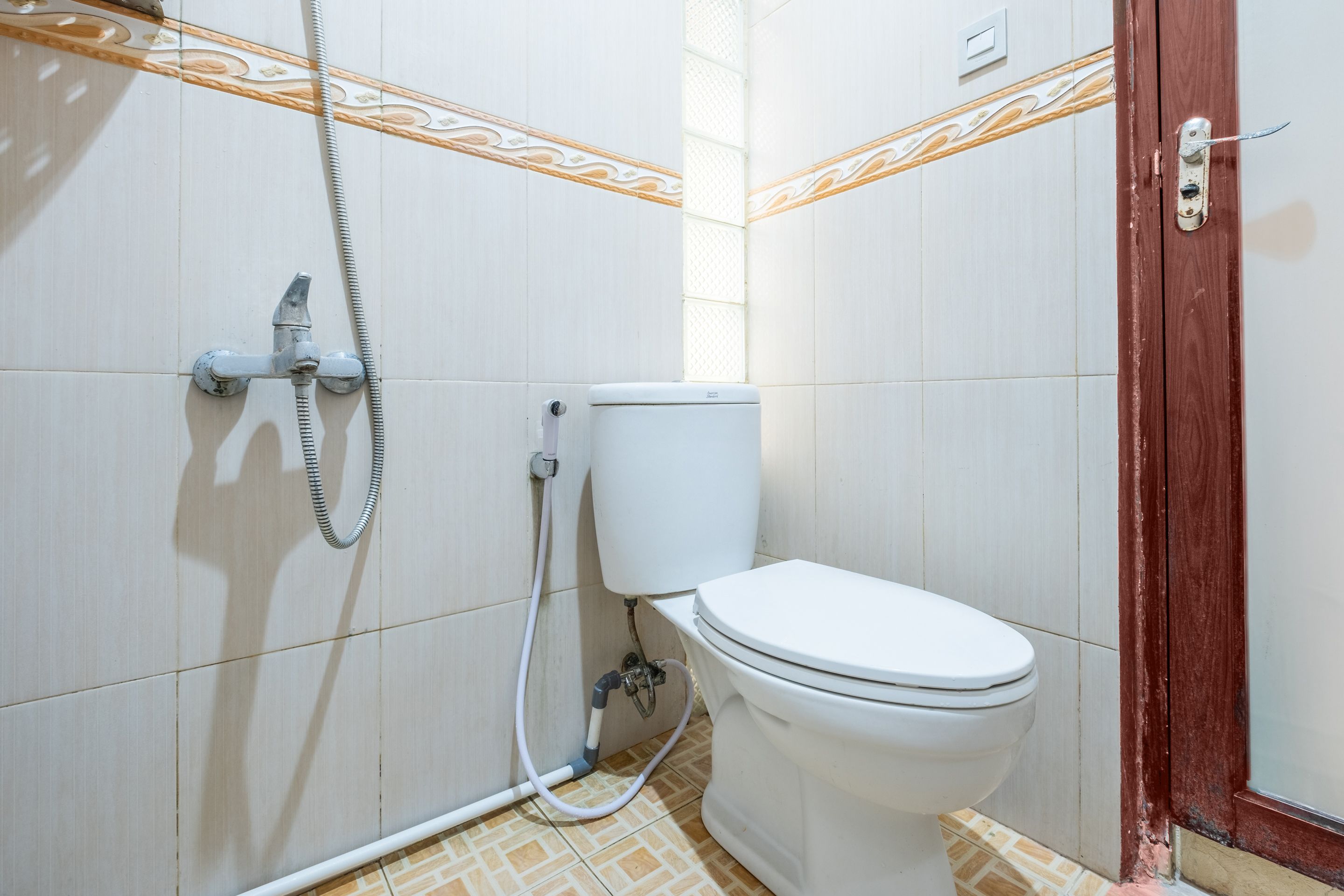 Un baño con inodoro, ducha y puerta de madera.