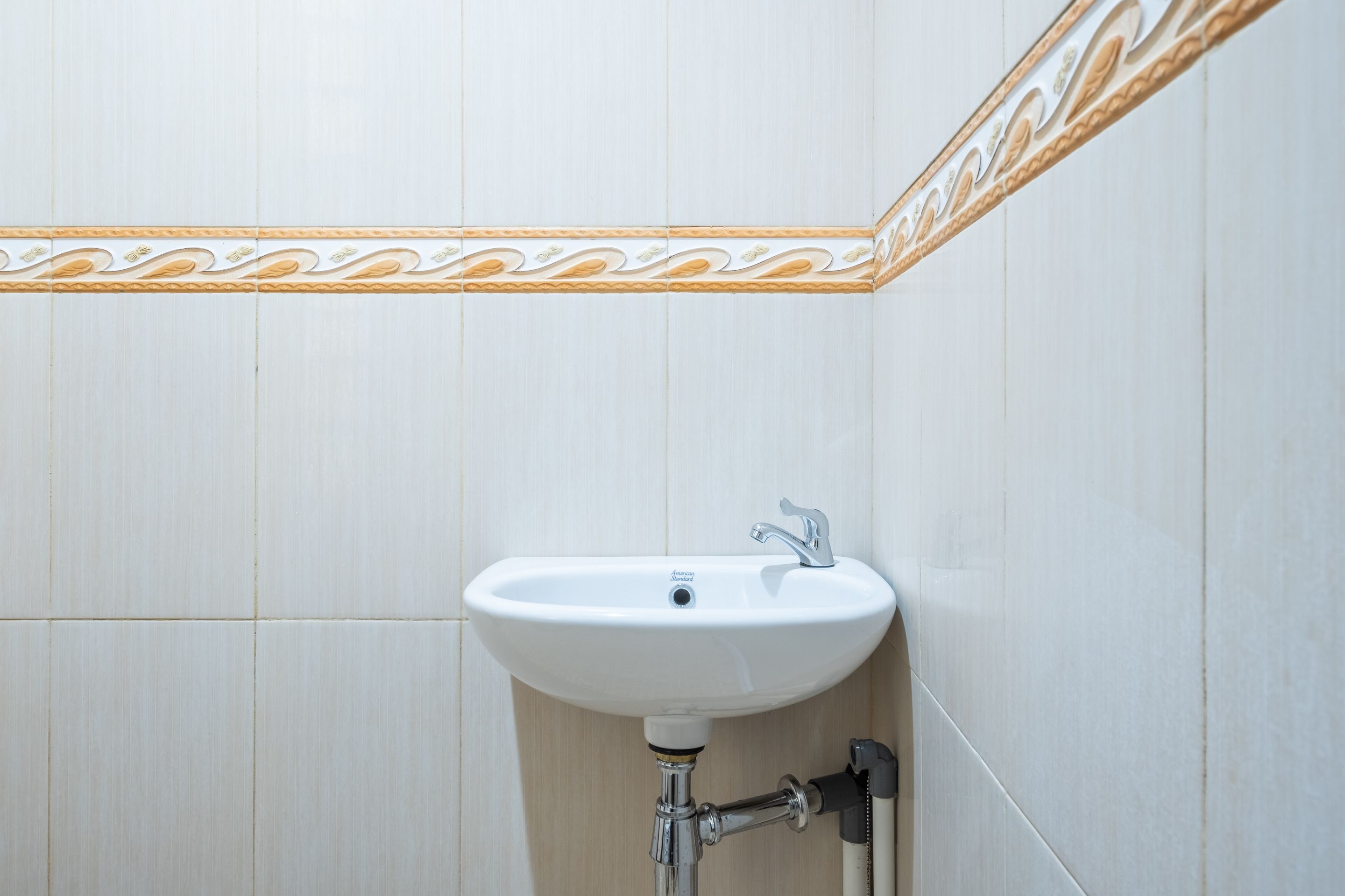 Un baño con lavamanos blanco, grifo y barra para toallas.