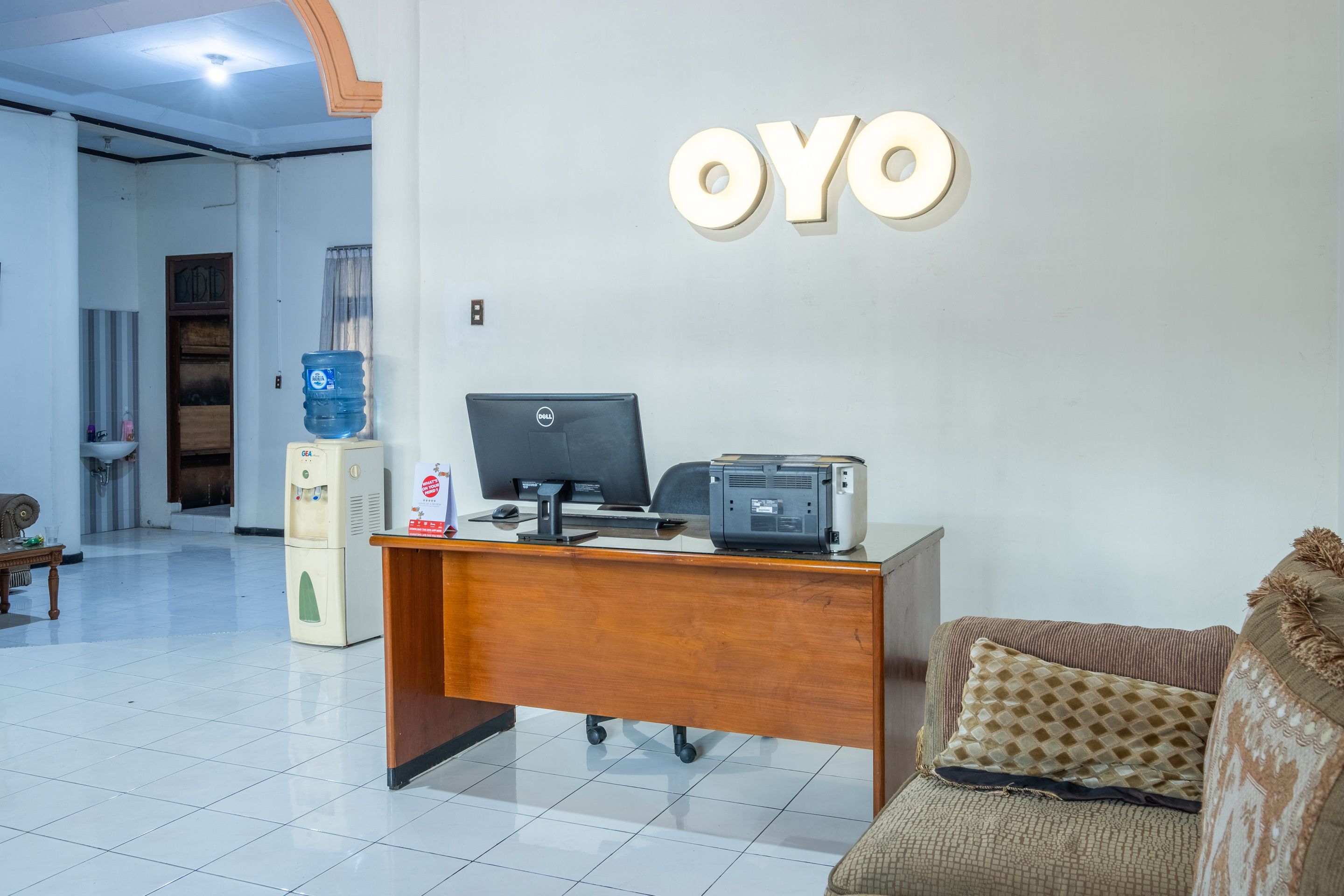 Un mostrador de recepción con una computadora Dell, un dispensador de agua e impresora.