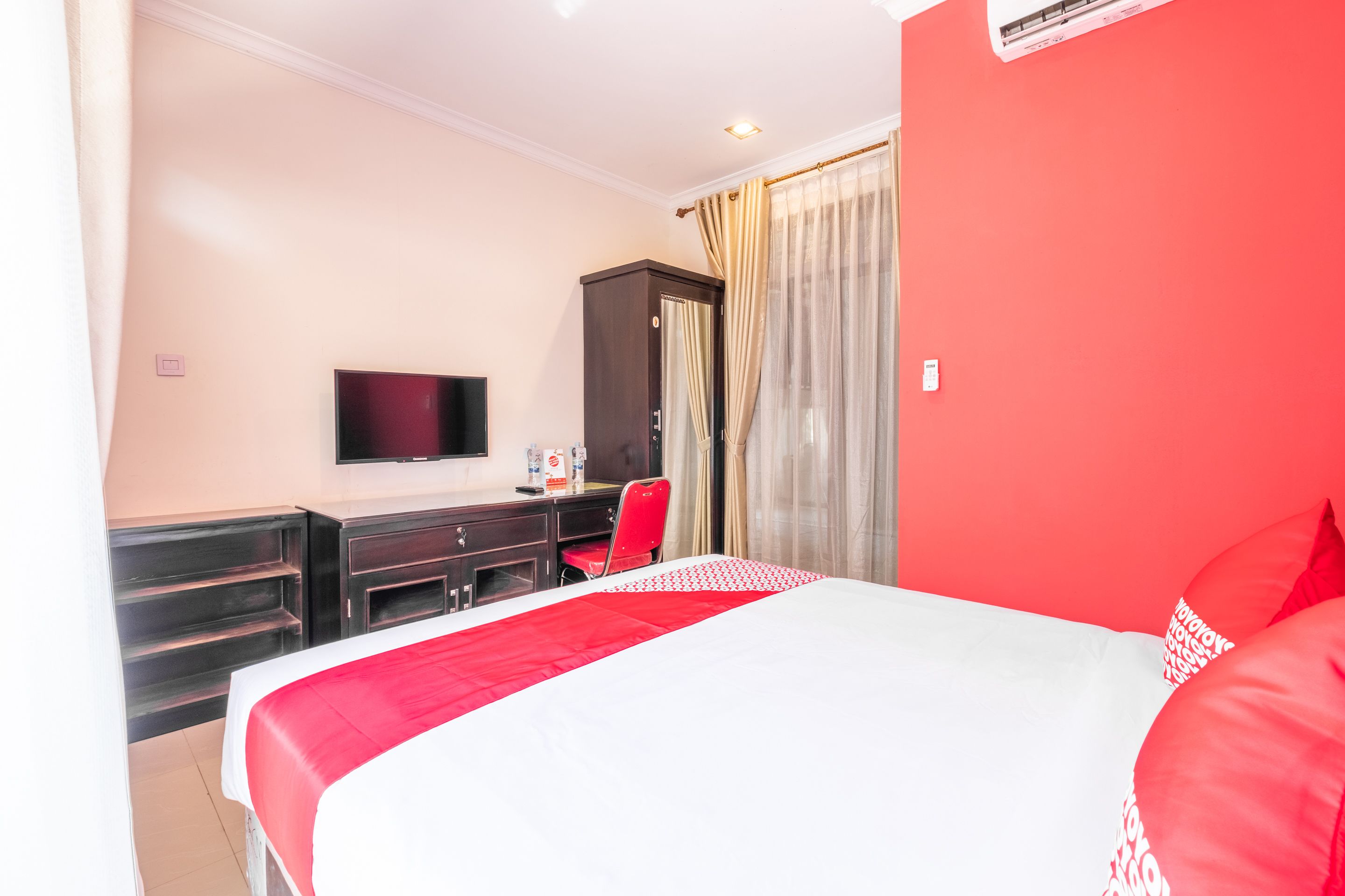 A hotel room with a bed, a TV, a desk, and a wardrobe.