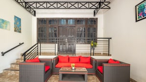A living area with wicker furniture, a central coffee table, and a staircase leading to an upper floor. - OYO Collection O 1032 Rahayu Residence Syariah (West Cirebon)