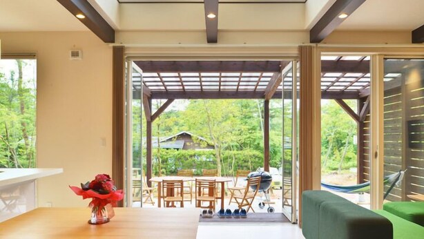 A modern interior with a wooden table, chairs, and a grill outside. - Family Cottage NOTOIE (Shika)