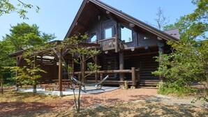 A log cabin with a porch, outdoor seating, and a hammock. - Family Cottage NOTOIE (Shika)