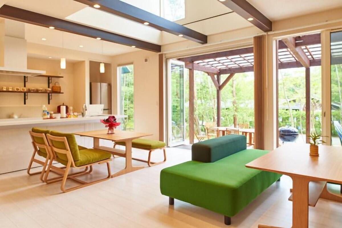 A modern kitchen with a dining area, large windows, and a wooden pergola.
