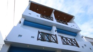 Un edificio moderno de varios pisos con techo plano, balcones con barandillas de madera y una decoración en tonos azules y blancos.