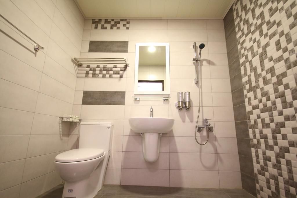 A small, tiled bathroom with a toilet, sink, and shower.