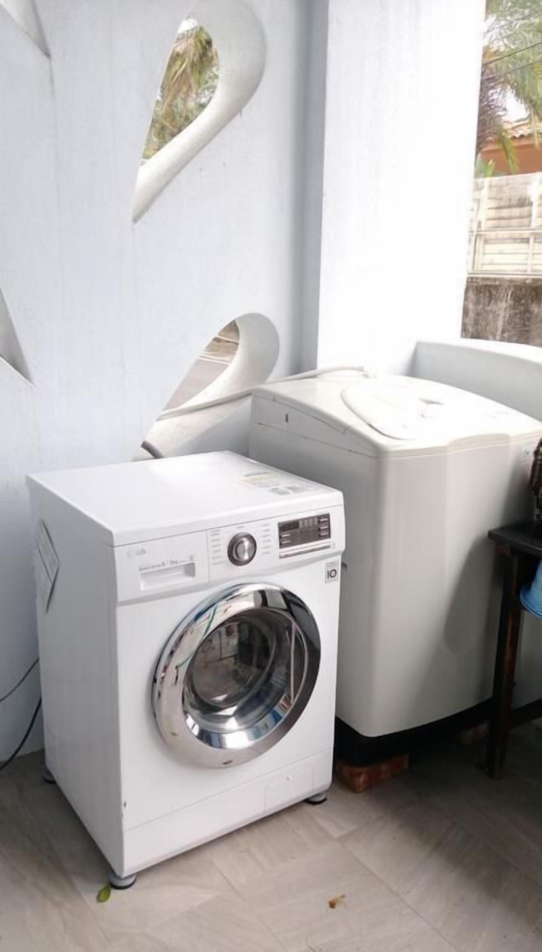 Uma área de lavanderia compacta com máquina de lavar frontal e secadora empilhada.