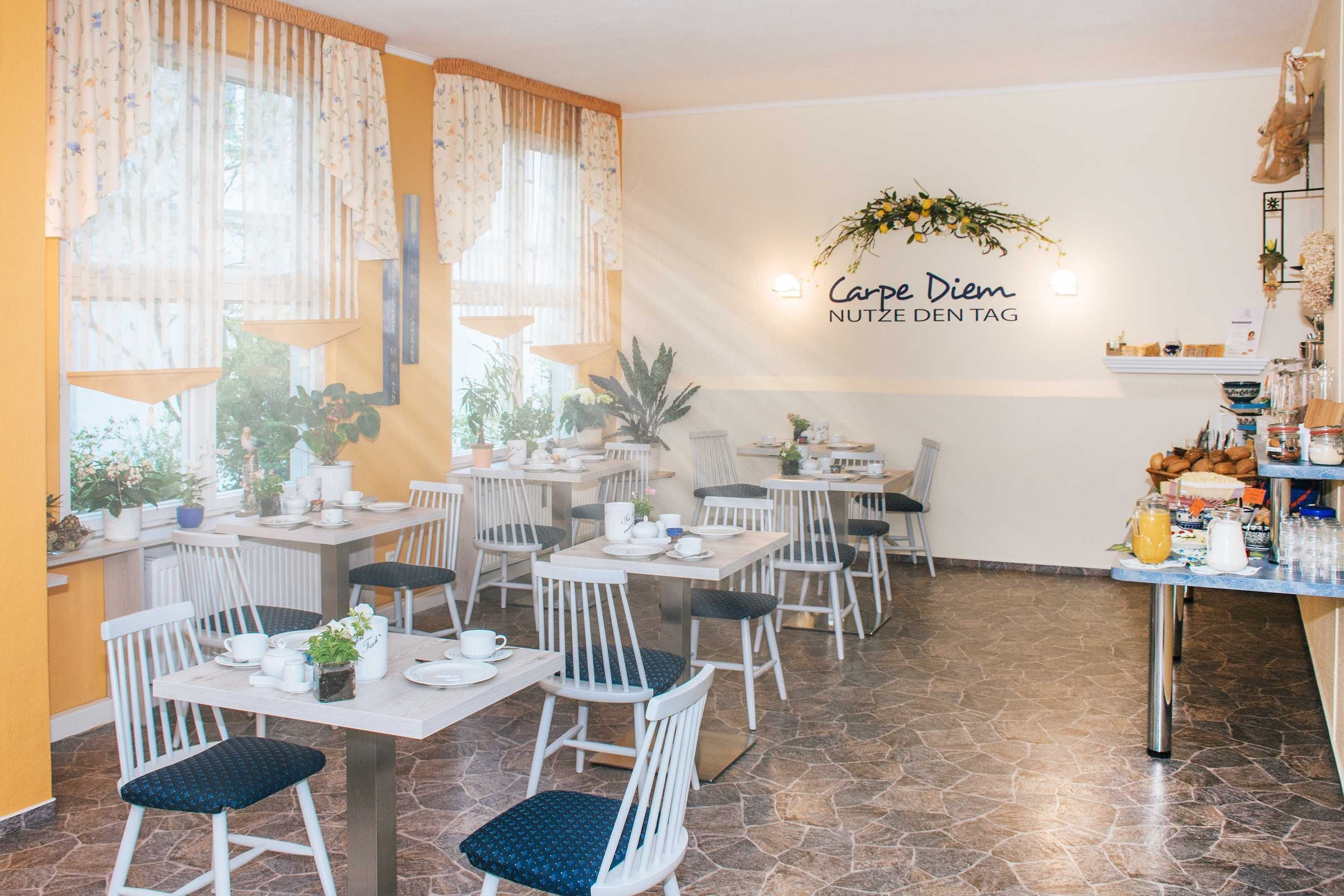 Un restaurante con sillas y mesas blancas, un letrero en la pared que dice 