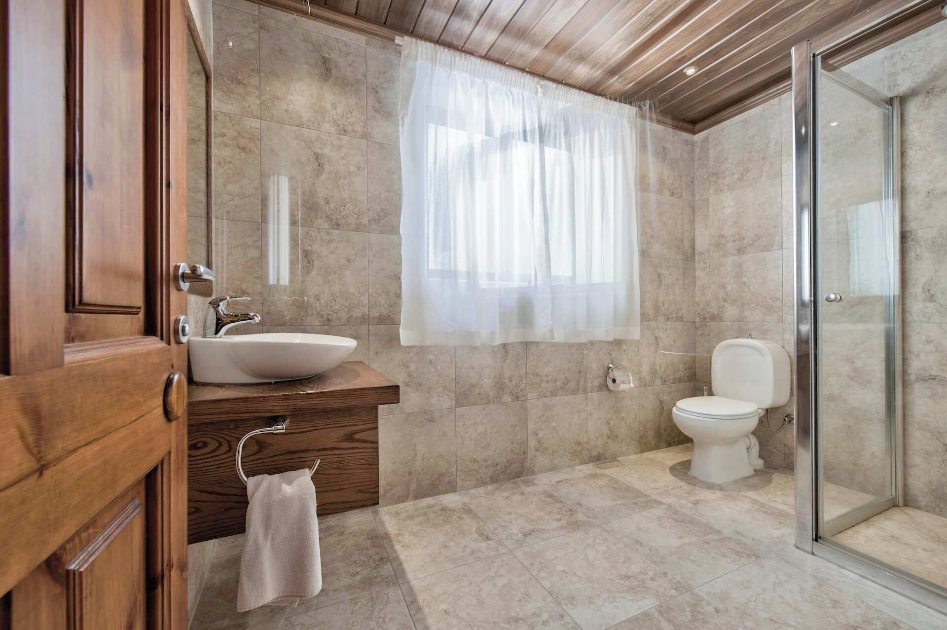 Une salle de bain avec un meuble-lavabo en bois, un évier, des toilettes et une douche à parois de verre.