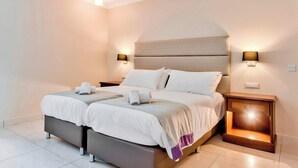 A double bed with a headboard, two bedside tables, and a nightstand with a lamp.