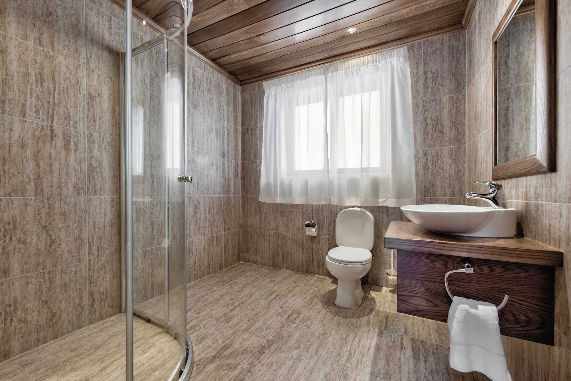 A modern bathroom with a glass-enclosed shower, a toilet, and a vanity with a sink and mirror.