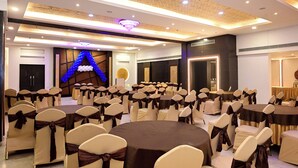 Une salle de banquet avec des tables et des chaises rondes, un mur décoratif et un éclairage encastré.