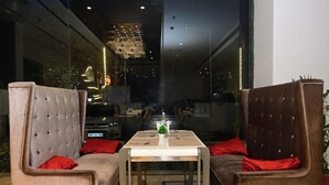 Un intérieur moderne avec deux fauteuils rembourrés, une table et une vue à travers un mur de verre.