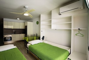 A compact room with two beds, a kitchenette, and a ceiling fan. - D010 Seaside view Las Vistas TRG Tenerife Royal Gardens (Playa de la Américas)