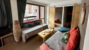 A cozy room with a bed, a small table, and a window with curtains.