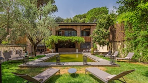 A modern house with a swimming pool, surrounded by lush greenery and equipped with outdoor seating. - Fauno Urban Resort (Rome)