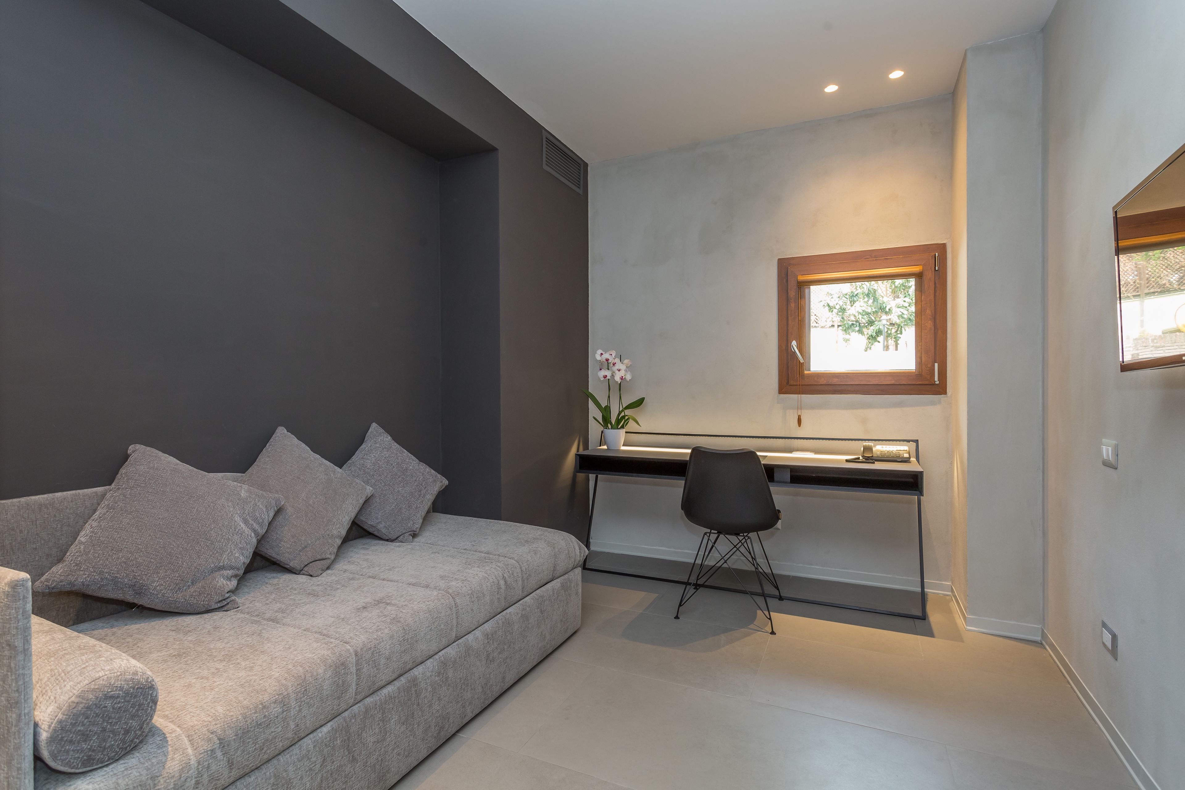 Un salon moderne avec un canapé gris, un petit bureau et une chaise.